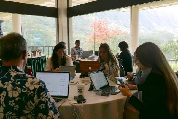 A group of people sitting around a table writing on laptops