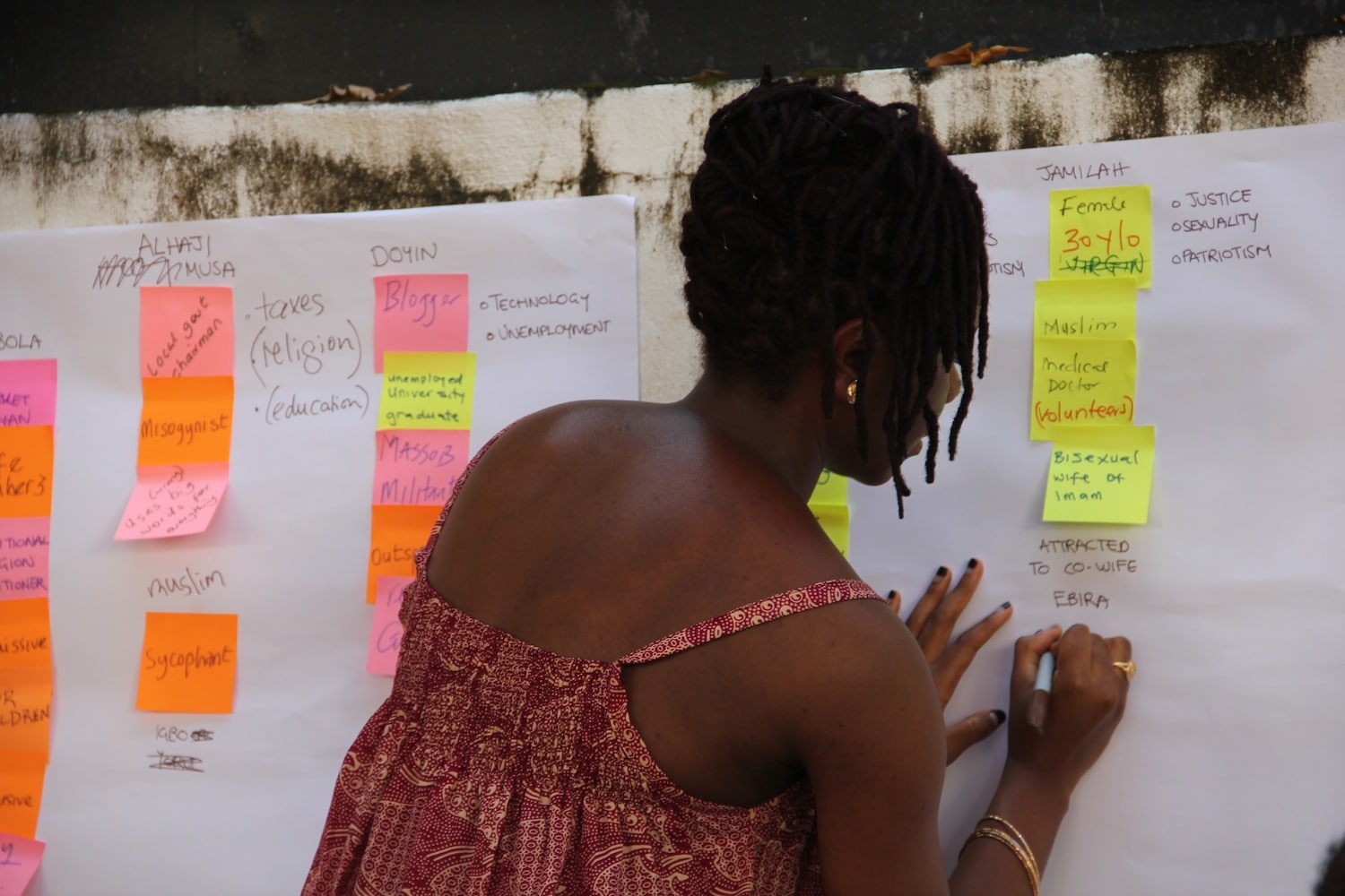 A woman writing on a whiteboard with sticky notes at a Book Sprint in Nigeria