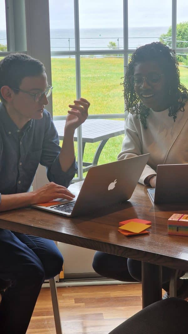 Two people sitting on their laptops, engaged in conversation and laughter