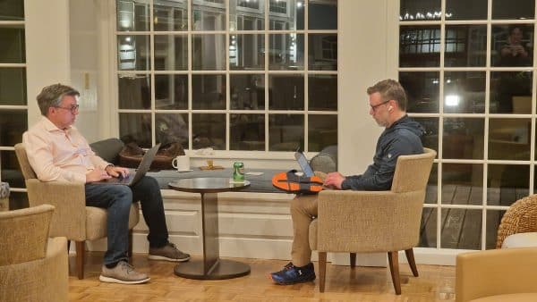 Two men sitting in armchairs working on their laptops.