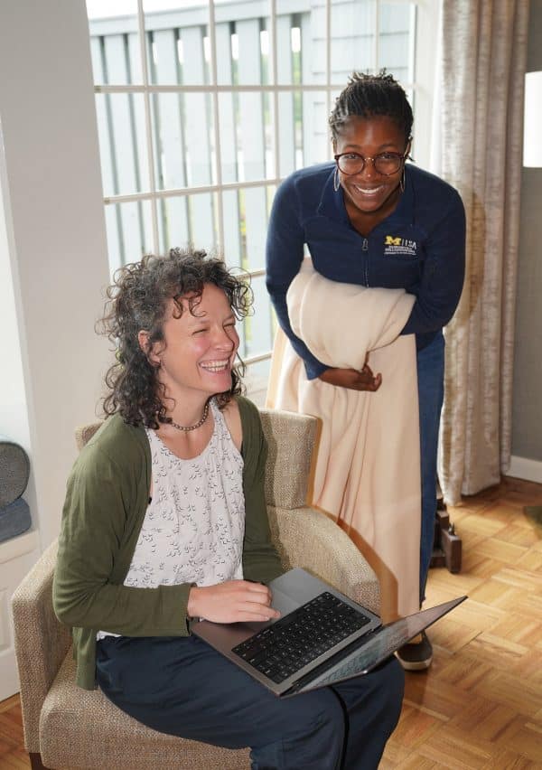 Two women sitting with a laptop and laughing
